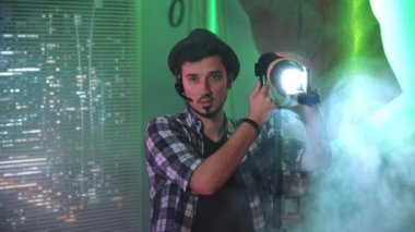 Film yapımcısı Fresnel lambası kullanırken kameraya bakıyor