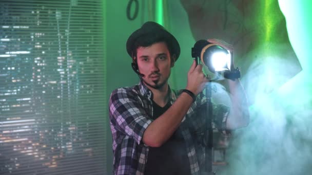 Κινηματογραφιστής κοιτάζοντας την κάμερα, ενώ χρησιμοποιώντας μια λάμπα Fresnel — Αρχείο Βίντεο