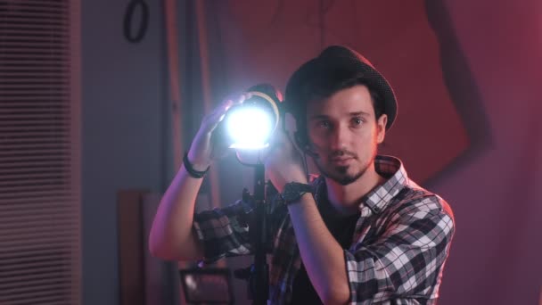 Male filmmaker adjusting professional light stand in studio, with lighting on — Stock Video