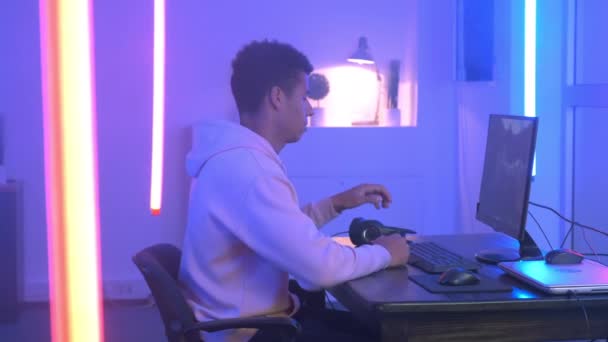 Profile view of handsome multiracial gamer taking headphones on — 비디오