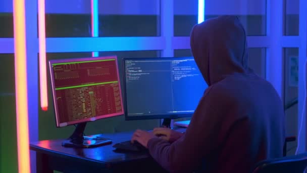 Μέτριο πλάνο του hacker ντυμένος σε ένα σκοτεινό κοντά εργασίας στον υπολογιστή. — Αρχείο Βίντεο