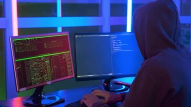 Close-up shot of of hacker dressed in a dark close working on computer
