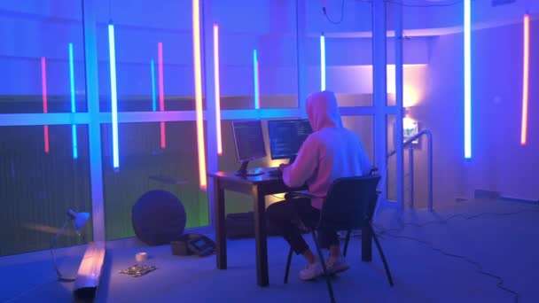 Hacker werkplaats: hacker werken in een kamer met gekleurde neon lichten — Stockvideo