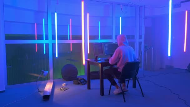 Hacker in witte hoodie penetrerende netwerk systeem in neon kamer — Stockvideo