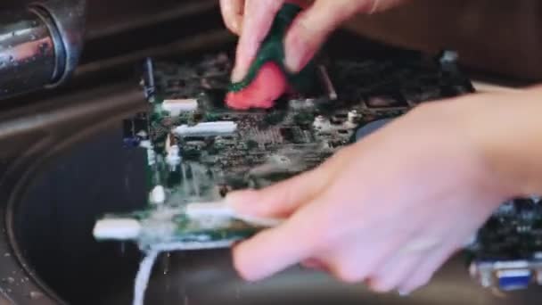 Hands rinses off motherboard dirt using water under the tap — Stock Video