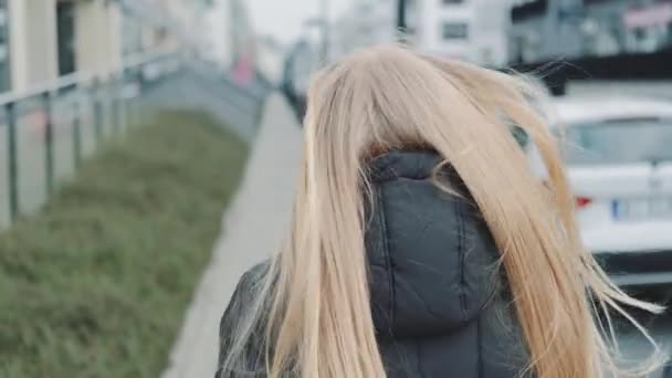 Młoda blondynka w masce medycznej ucieka przed kimś na ulicy. — Wideo stockowe