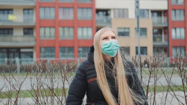 Blonde fille dans un masque médical assis sur le banc . — Video