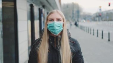 Sokakta koruyucu bir maske takan genç sarışın kadın.