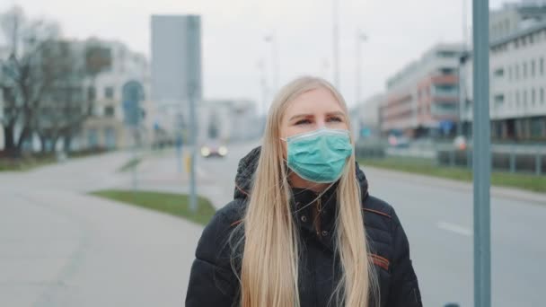Занепокоєна жінка в медичній коронавірусній масці, що йде по вулиці — стокове відео