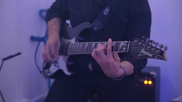 El hombre está tocando la guitarra eléctrica sentado profesionalmente . — Vídeos de Stock