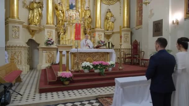 Sacerdote está orando con recién casados en la iglesia católica . — Vídeos de Stock