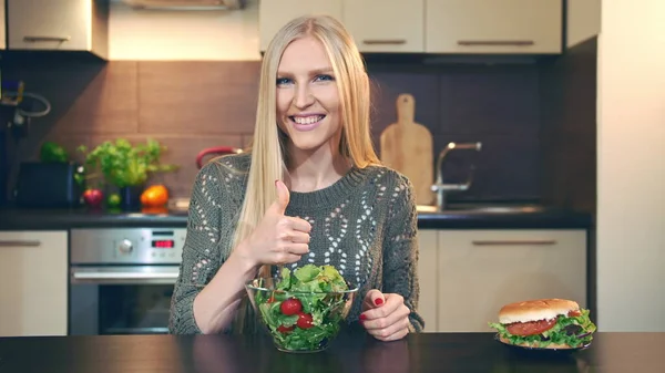 Girl preferring salad to hamburger.