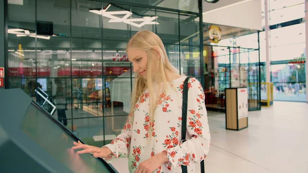 Jovem mulher procurando direção certa no tabuleiro de navegação no shopping moderno . — Fotografia de Stock