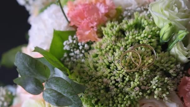 Свадебные кольца, лежащие на вершине цветов . — стоковое видео