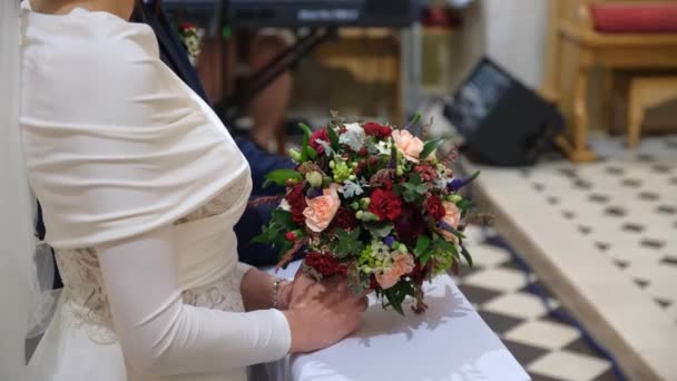 Gelin kilisede dua ediyor. Elinde düğün buketi var.. — Stok video
