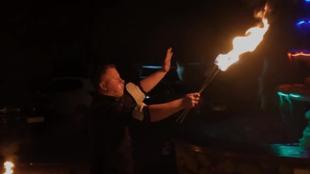 De mens toont gevaarlijke goocheltrucs met vuur en blaast vuur uit zijn mond. — Stockvideo