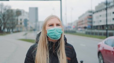 Tıbbi koronavirüs maskeli endişeli bir kadın sokakta yürüyor.
