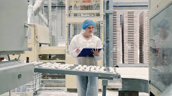 Denetçi, taşıyıcıyı şekerlemelerle kontrol ediyor. Şeker fabrikası.