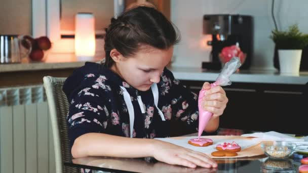 Menina bonita decorar biscoitos com cor de açúcar esmalte à noite em casa — Vídeo de Stock