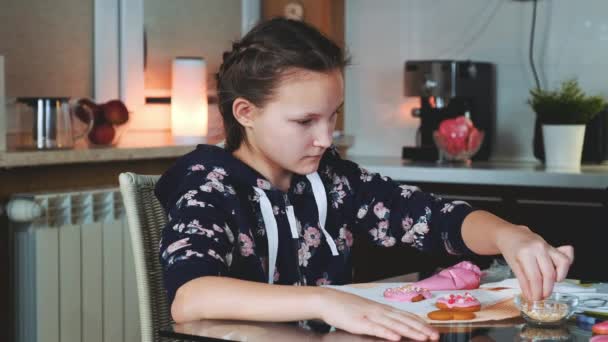 Χαρούμενη νεαρή κοπέλα βοηθώντας τη μητέρα της να διακοσμήσει τα μπισκότα για τον εορτασμό των διακοπών — Αρχείο Βίντεο