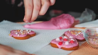 Çocuk dekore eden kalp şeklindeki kurabiyelerin üzerine tatlı renk serpiştirilmiş..