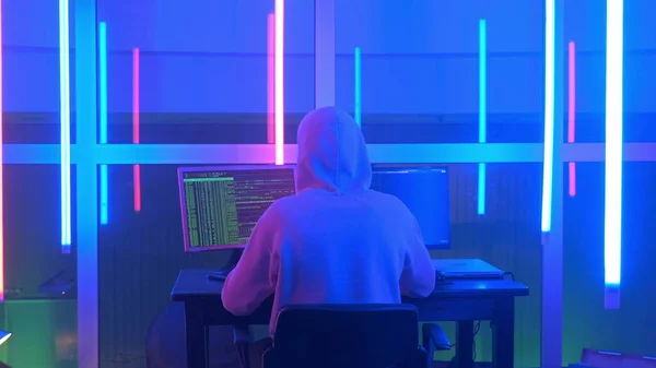 Medium back view shot of criminal hacker working in the evening on computer in big office — Stockfoto