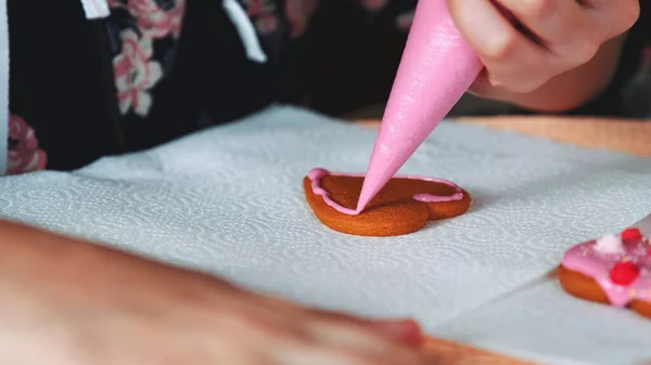 Processo di decorazione di biscotti a forma di cuore con glassa di zucchero rosa — Foto Stock