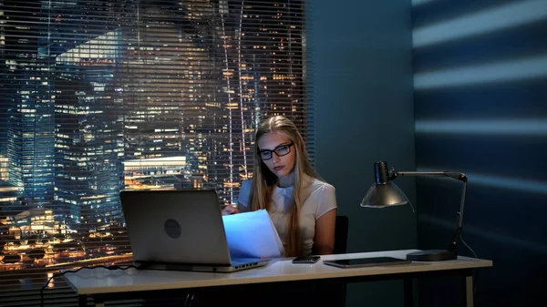 Joven profesora corrigiendo su informe a altas horas de la noche y comprobando el smartphone — Foto de Stock