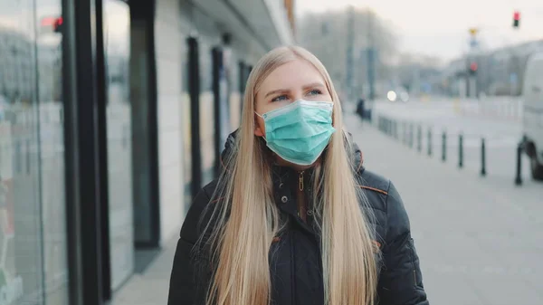 Sokakta koruyucu bir maske takan genç sarışın kadın. — Stok fotoğraf