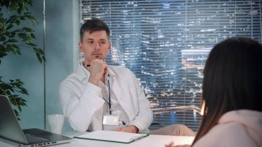 Omzunun üstünden. Laboratuvar önlüklü erkek psikolog hastayı dinliyor ve notlar alıyor.