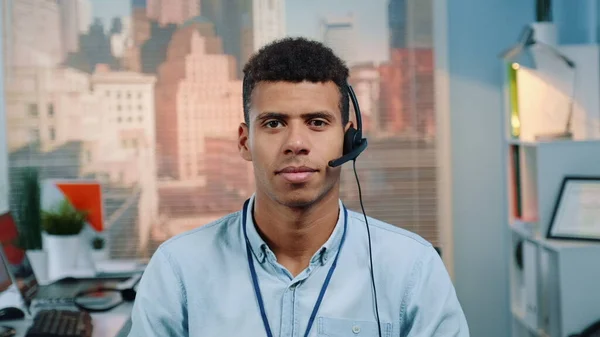Portrait of mixed-race customer service operator in a headset smiling to the camera