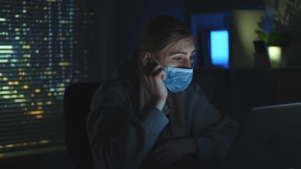 Närbild bild av Rädd kvinna i medicinsk mask läsa nyheter om coronavirus på laptop i mörker — Stockvideo