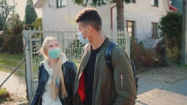 Blonde woman and african man in protective masks strolling through the residential area — Stock Video