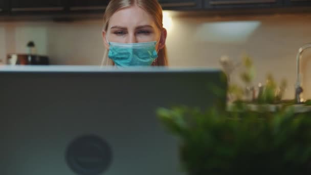 Framifrån på datorskärm och kvinna i medicinsk mask läser något på den — Stockvideo