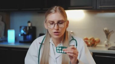 Hastaya video çağrısı: tıp önlüklü kadın doktor kameraya bakıyor ve nasıl ilaç alınacağını anlatıyor.