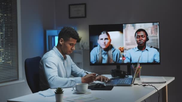 Fekete vezérigazgató videóhívást csinál nagy monitoron, karanténban lévő kollégáival. — Stock videók