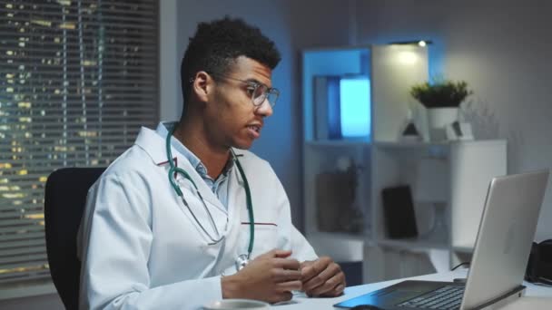 Молодой африканский врач показывает, как носить медицинскую маску по видеосвязи на компьютере — стоковое видео