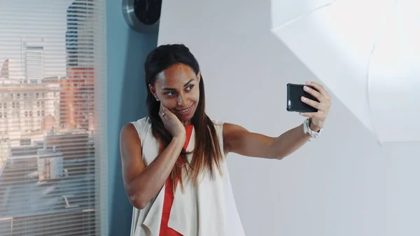 In photo shoot break beautiful african model making selfie on smartphone in professional studio — Stock Photo, Image
