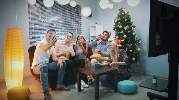 Jóvenes de raza mixta en los sombreros de Santa haciendo videollamada por teléfono inteligente en la fiesta de Navidad —  Fotos de Stock