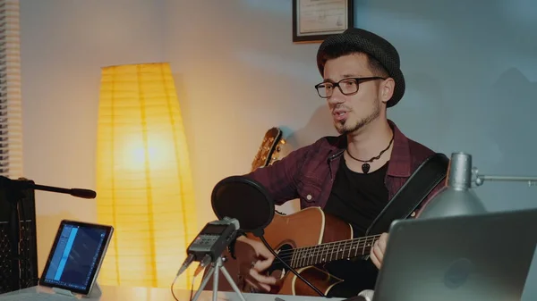 Giovane musicista allegro che suona la chitarra e canta nel microfono in studio domestico — Foto Stock