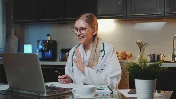 Kadın doktor, hastane önlüğü giymiş. Hastaneden hastaya video çağrısı yapıyor.