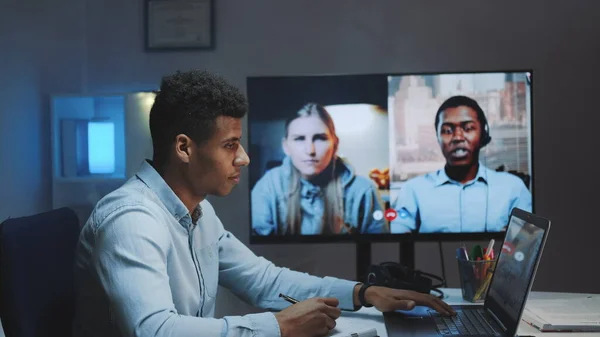 Zbliżenie na czarnego głównego menedżera wykonującego rozmowę wideo na dużym monitorze z kolegami na kwarantannie — Zdjęcie stockowe