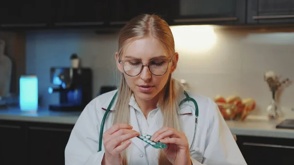 환자에게 알리는 영상 통화: 의료 복을 입은 여의사가 카메라를 보면서 약을 복용하는 방법을 설명하는 모습 — 스톡 사진