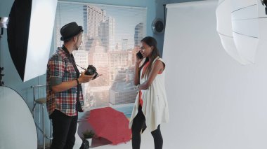 Fotoğraf çekiminin sahne arkası: güzel siyah model akıllı telefondan konuşmayı bıraktı ve çalışmaya başladı