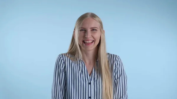 Lykkelig ung dame brister i latter på blå baggrund - Stock-foto