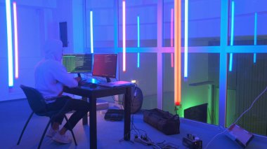 Hacker çalışma yeri: renkli neon ışıkları olan bir odada çalışan hacker