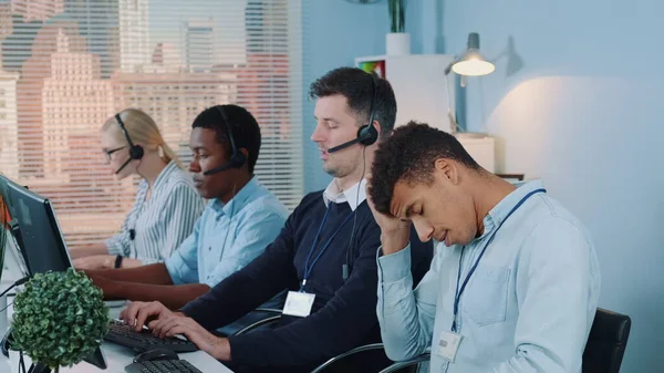 Multiracial call center agent feeling exhausted and broken-down after telephone call with the client.