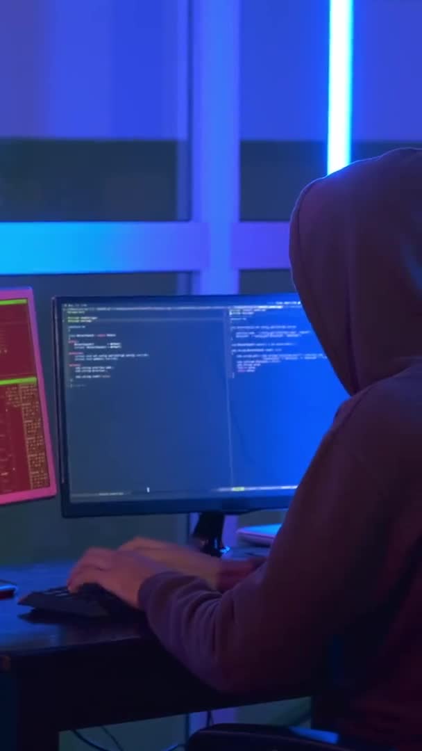 Vista trasera del hacker vestido con un cierre oscuro trabajando en la computadora — Vídeos de Stock