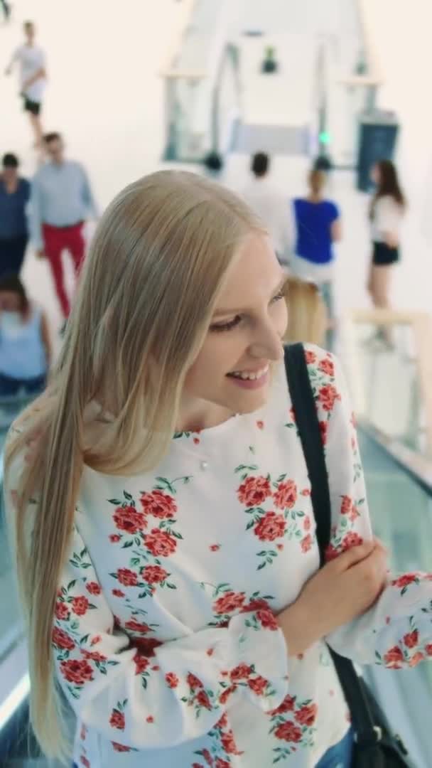 Mujer rubia joven montando en escaleras mecánicas . — Vídeos de Stock