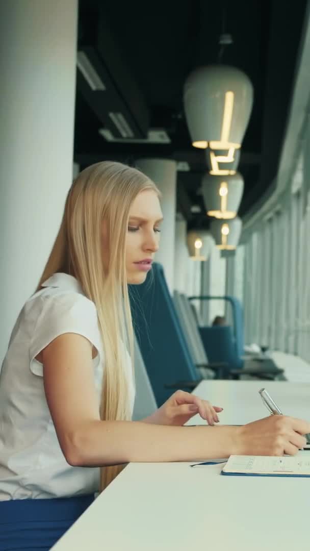 Podnikatelka pracující s laptopem v nové kanceláři. Boční pohled na ženu sedící u stolu vedle okna v moderní kanceláři a používající notebook za denního světla. — Stock video